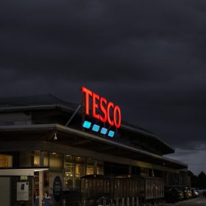 Tesco sign lit against a dark stormy sky at dusk Seaton 02_11_21