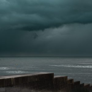 Sunlight and stormy sky over the sea wall and a blue sea at Cobb Gate, Lyme Regis 27_10_23