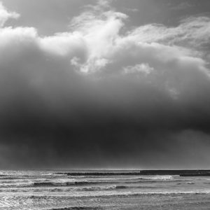 Stormy sky and sunlit sea over the Cobb from Front Beach, Lyme Regis 18_02_22 mono