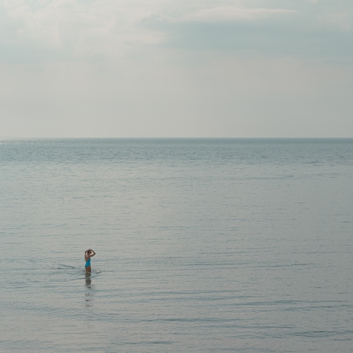Woman standing in the sea in morning sunlight off Cobb Gate Beach Lyme Regis 20_05_24 copy edit