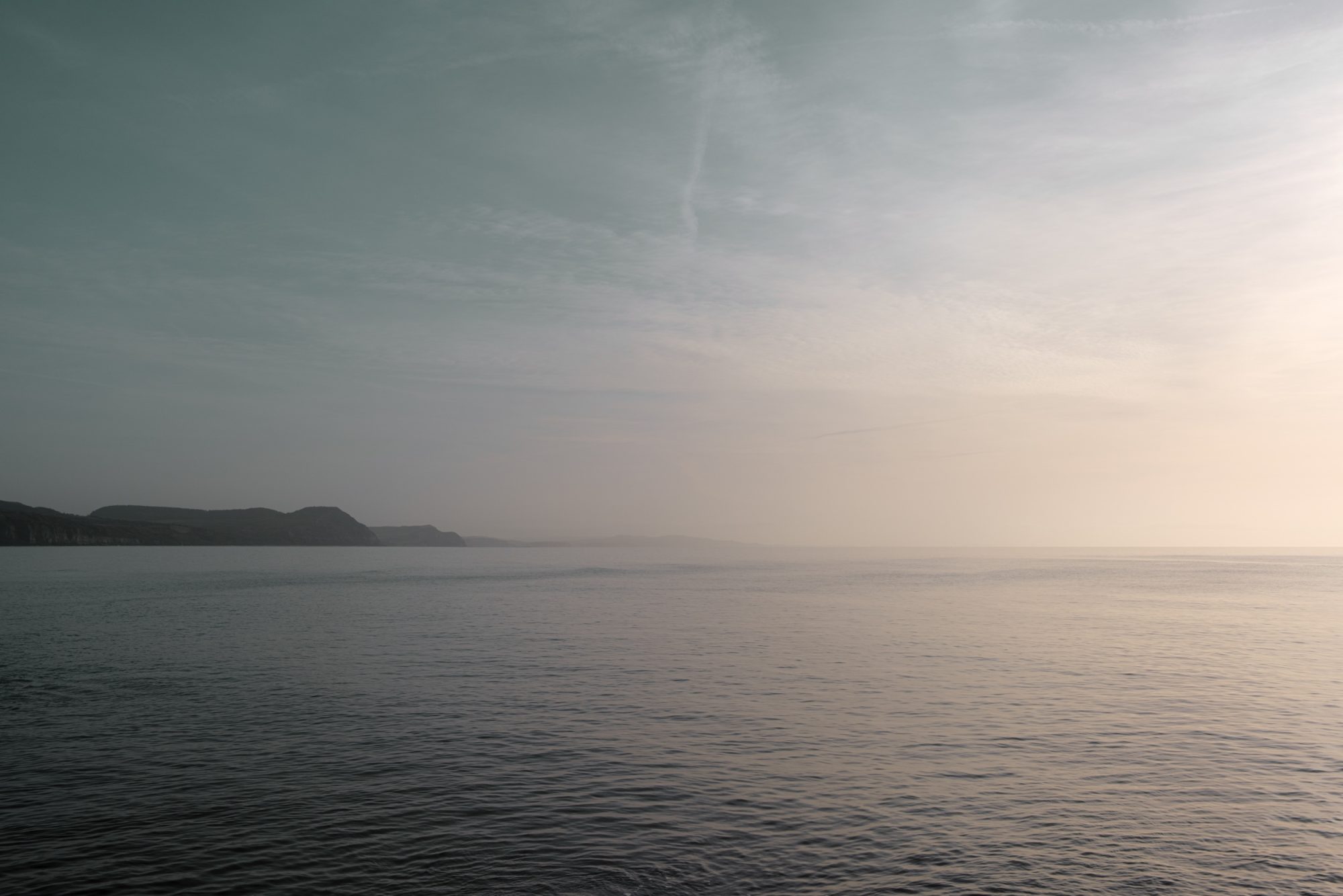 Hazy morning sunlight over the sea with the coast beyond from Front Beach Lyme Regis 01_02_24 edit
