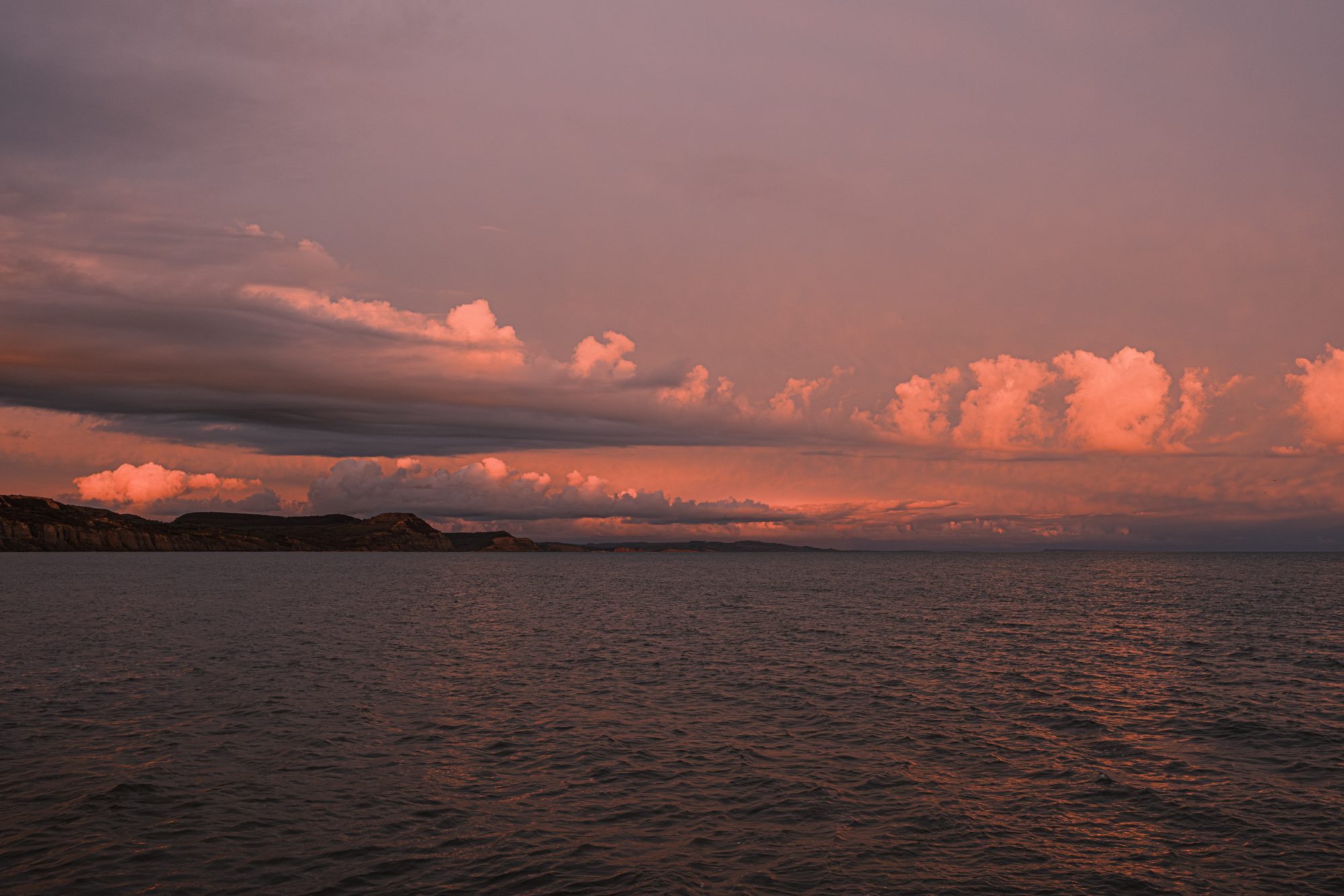 Orange tinted sunset cloudscape over the sea and coast from Gun Cliff Walk Lyme Regis 26_03_24